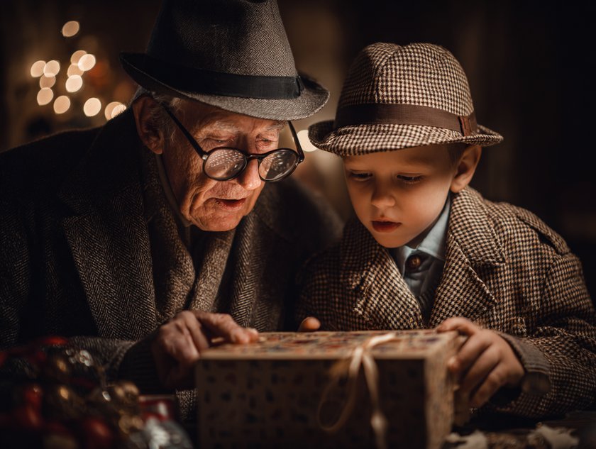 Boomer-Adventskalender: Großvater und Enkelsohn öffnen in Detektivkleidung einen Adventskalender