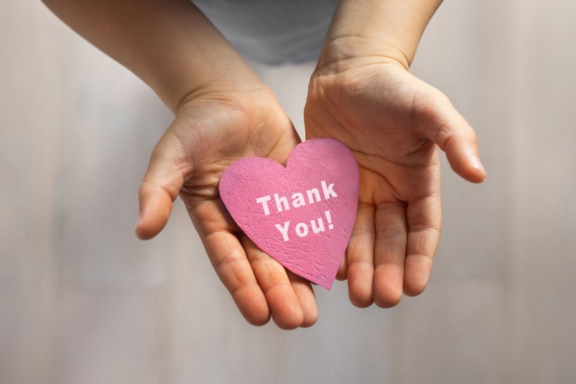 Hände halten ein rosa Papierherz mit einer Dankesbotschaft Hände halten ein rosa Papierherz mit einer Dankesbotschaft