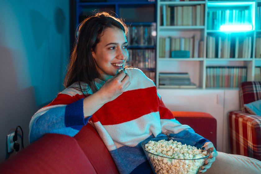 Junge Frau sitzt lachend vor dem Fernseher. Junge Frau sitzt lachend vor dem Fernseher.