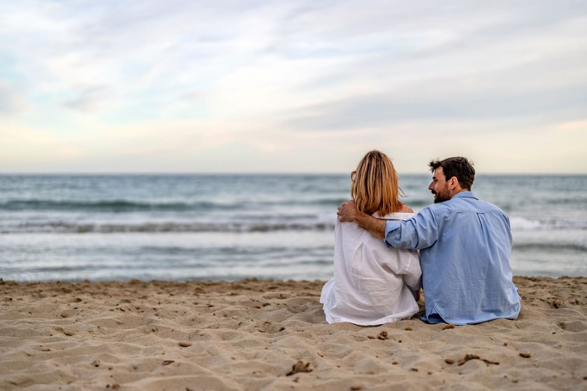 Partner sitzt mit seiner Partnerin gemeinsam am Strand Partner sitzt mit seiner Partnerin gemeinsam am Strand