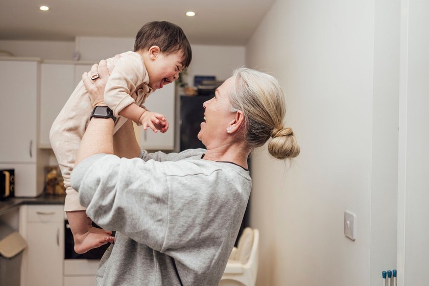 Moderne Boomer-Großeltern: Oma hält lachendes Baby hoch Moderne Boomer-Großeltern: Oma hält lachendes Baby hoch