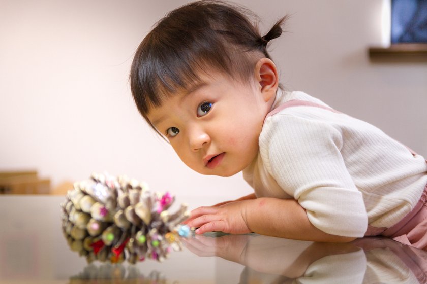 Montessori-Weihnachtskalender: Kleinkind mit Tannenzapfen
