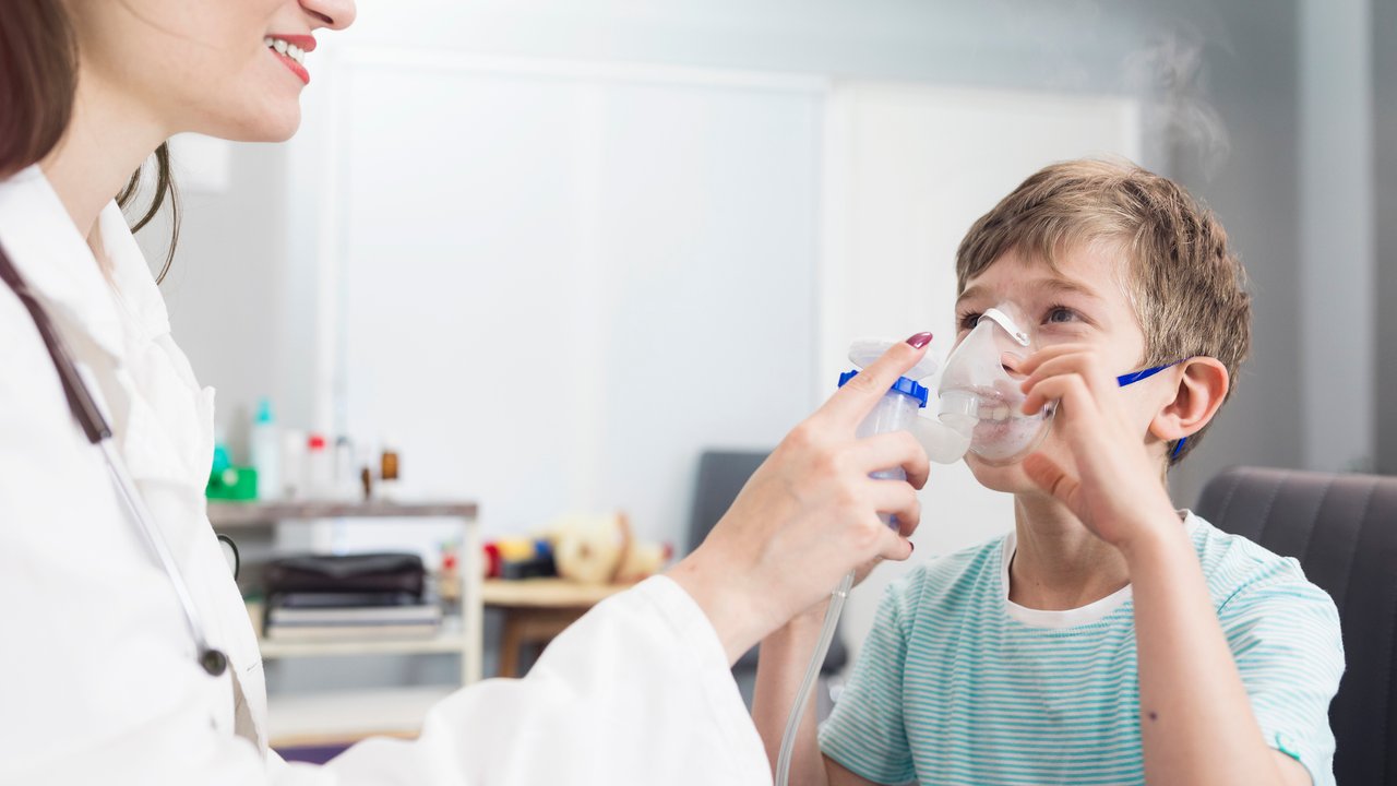 Doctor holding inhaler mask for kid breathing in pediatrician clinic