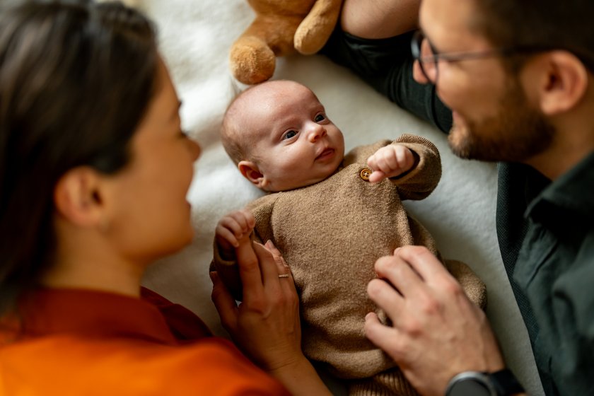 Happy parents playing with their newborn son on bed Happy parents playing with their newborn son on bed