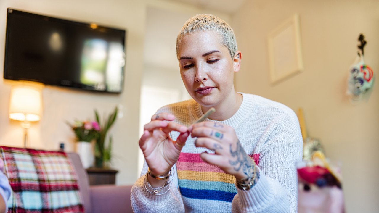 Junge blonde Frau mit Tattoos dreht sich einen Joint. Junge blonde Frau mit Tattoos dreht sich einen Joint.