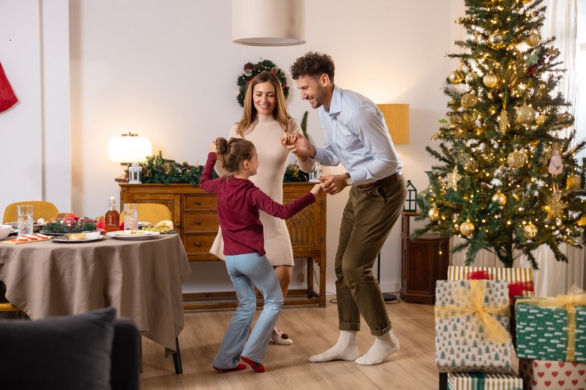 Spiele für die Festtage für Kinder: Familie spielt zu Weihnachten gemeinsam ein Spiel