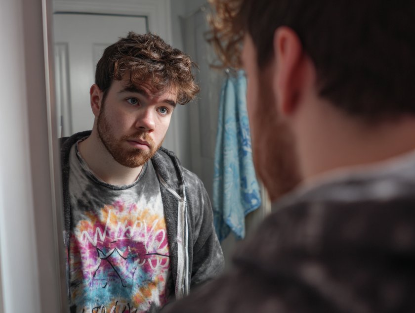 Mann schaut unsicher in Spiegel