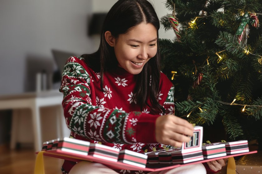Adventskalender-Sprüche: Junge Frau öffnet ihren Adventskalender