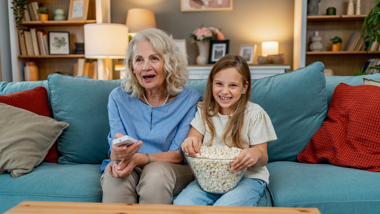 Grandmother with her granddaughter watching TV in the living room
