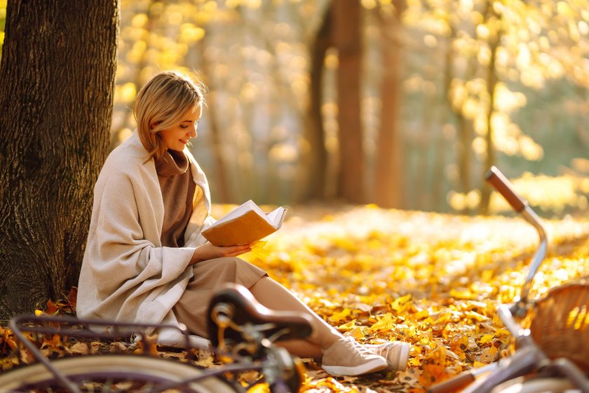 Junge Frau liest ein Buch im Herbst im Park Junge Frau liest ein Buch im Herbst im Park