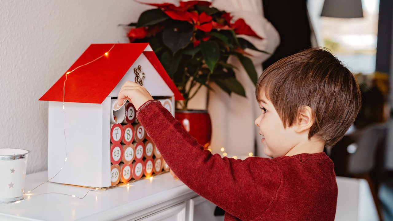 Little happy child opening first day in handmade advent calendar made from toilet paper rolls. Sustainable Christmas, upcycling, zero waste, kids seasonal activities Little happy child opening first day in handmade advent calendar made from toilet paper rolls. Sustainable Christmas, upcycling, zero waste, kids seasonal activities