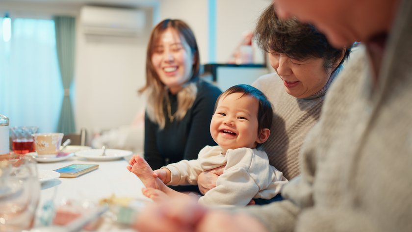 Lieblingsoma werden: Familie mit Baby lachend am Tisch Lieblingsoma werden: Familie mit Baby lachend am Tisch