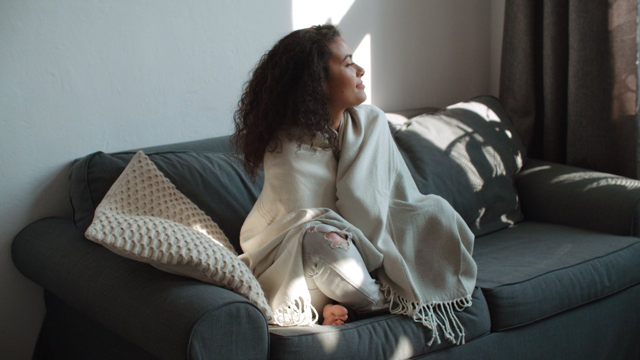 Einnistungsschmerz: Frau kuschelt auf Couch