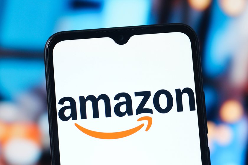 Amazonlogo auf Handydisplay und Lichter im Hintergrund Amazonlogo auf Handydisplay und Lichter im Hintergrund