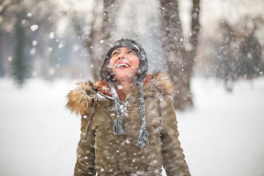 Resilienz stärken: Lachende Frau im verschneiten Wald