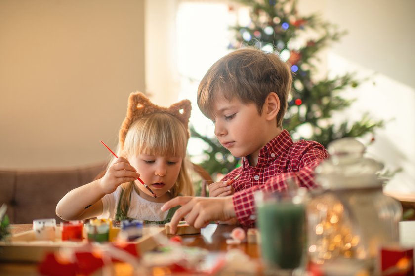 DIY-Winterdeko für Kinder: Kinder bemalen Holzspielzeug in einem weihnachtlich dekorierten Raum. DIY-Winterdeko für Kinder: Kinder bemalen Holzspielzeug in einem weihnachtlich dekorierten Raum.