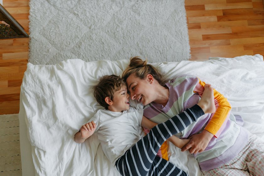 Liebesbeweise Kinder: Mama kuschelt mit Kind im Bett