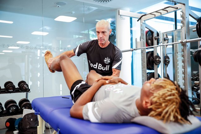 Physiotherapeut renkt Mann auf Liege ein Bein ein Physiotherapeut renkt Mann auf Liege ein Bein ein