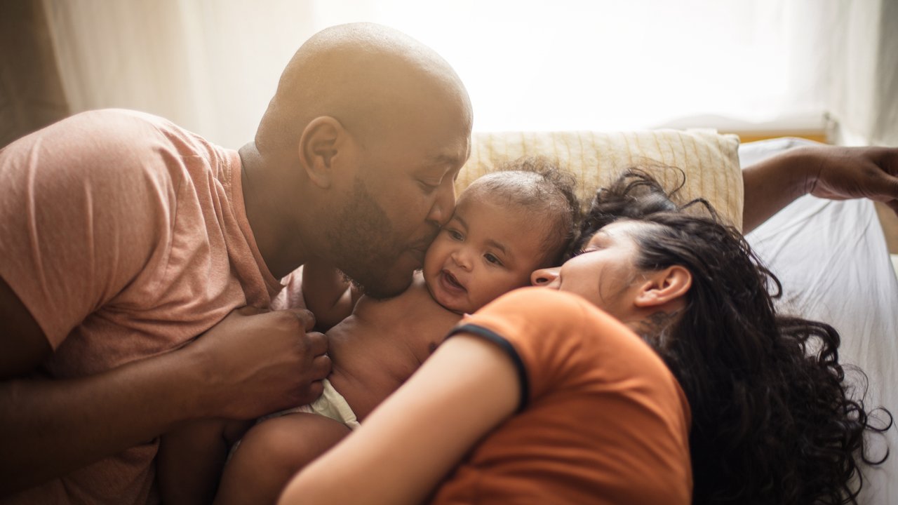 Wochenbett Checkliste: Familie mit Baby im Bett