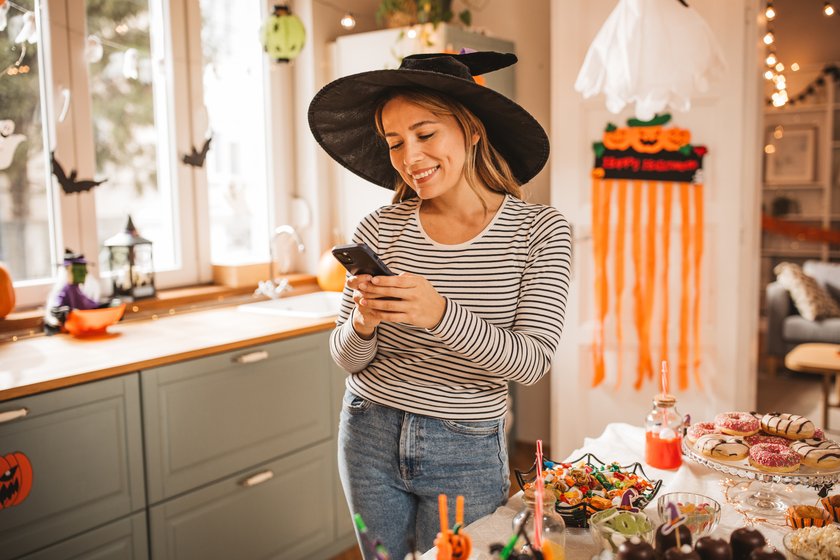 Mature woman in costume setting table for Halloween lunch, she is photographing it with smart phone. Mature woman in costume setting table for Halloween lunch, she is photographing it with smart phone.