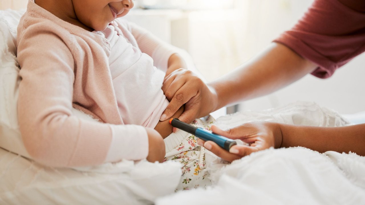 Diabetes Typ 1 bei Kindern: Mama misst Blutzucker bei ihrer Tochter
