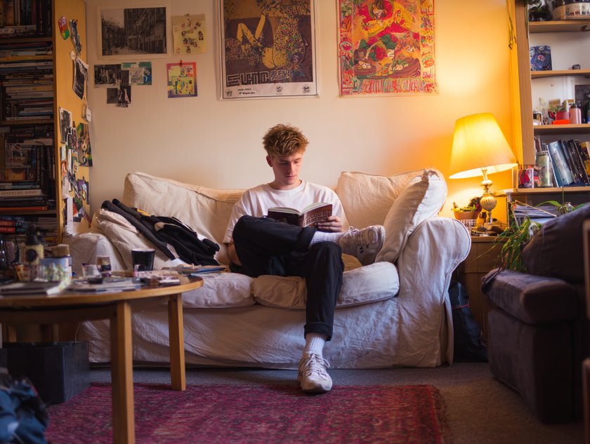 Gen Z Mann liest Buch auf Couch