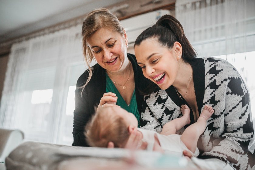 Moderne Boomer-Großeltern: Mama und Oma wickeln Baby Moderne Boomer-Großeltern: Mama und Oma wickeln Baby