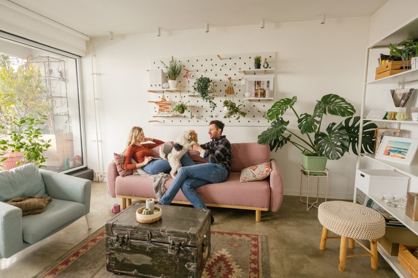 Junge Familie mit Hund sitzt in ihrer stylischen Wohnung auf dem Sofa Junge Familie mit Hund sitzt in ihrer stylischen Wohnung auf dem Sofa