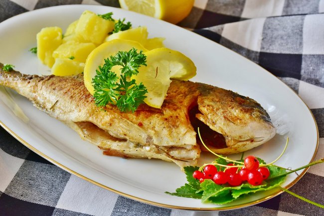 Ein Teller mit gebratener Dorade, Kartoffeln und Zitrone. Ein Teller mit gebratener Dorade, Kartoffeln und Zitrone.