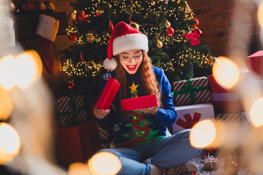 Hübsche Frau mit Nikolausmütze freut sich über ein Nikolausgeschenk