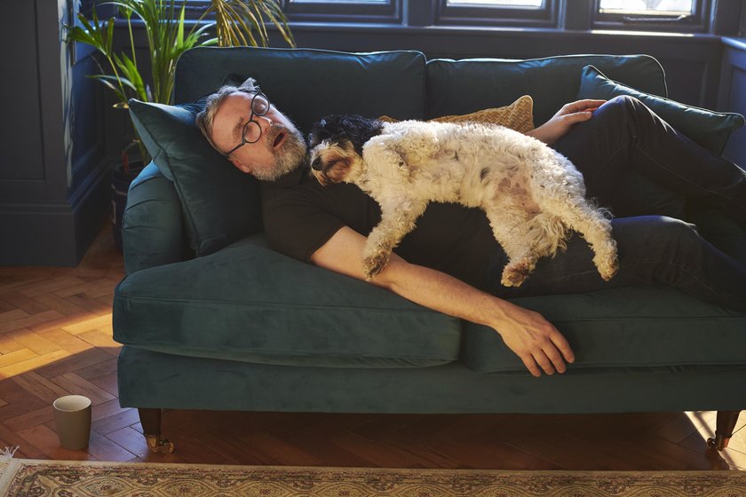 Mann hält Nickerchen auf der Couch mit seinem Hund Mann hält Nickerchen auf der Couch mit seinem Hund