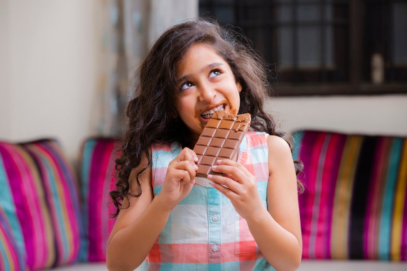 DDR-Schokolade: Mädchen beißt in Tafel Schokolade