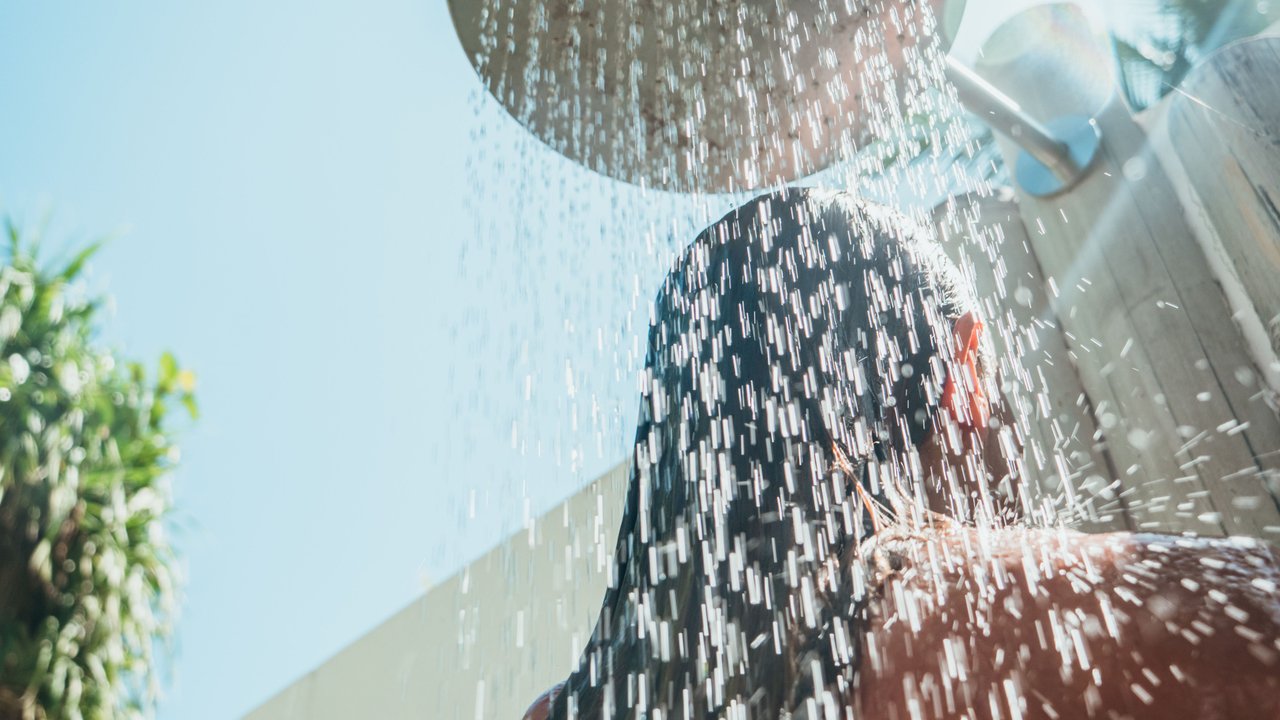 Frau duscht sich unter einer Solardusche ab