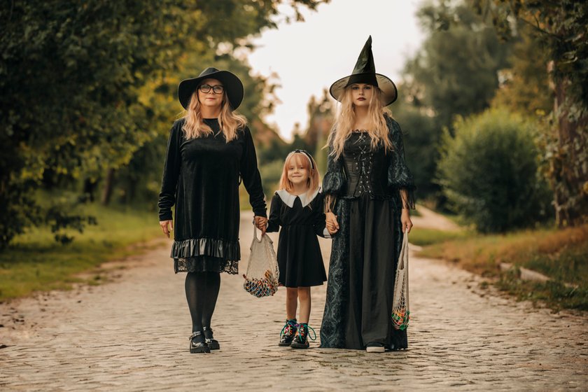 Family dressed as witches celebrating Halloween outdoors in village. Family dressed as witches celebrating Halloween outdoors in village.
