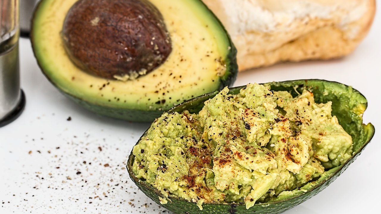 Eine aufgeschnittene Avocado mit Kern und gewürztem Fruchtfleisch. 