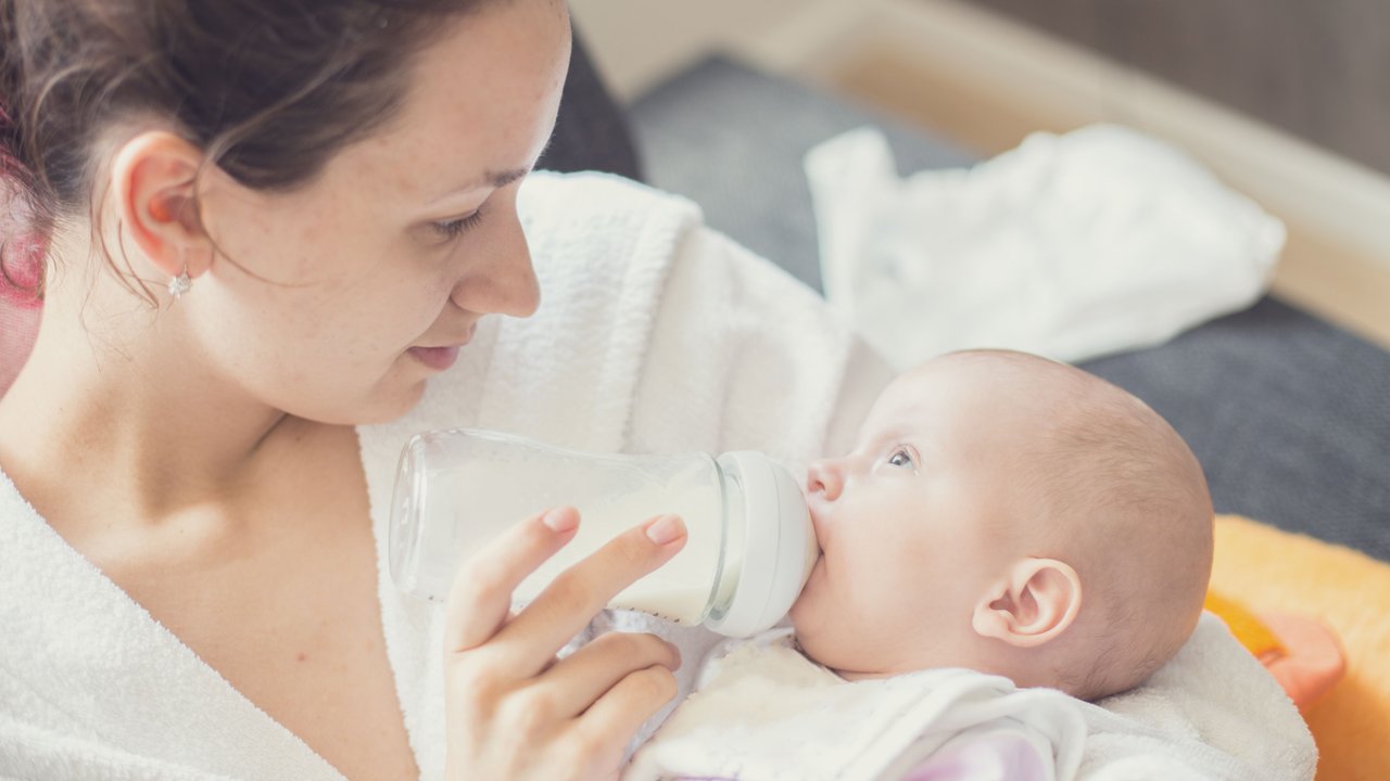 Frau füttert Baby mit Flasche
