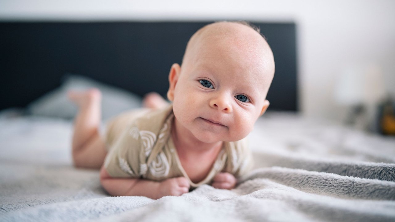 Close up portrait of cute baby boy laying on front and looking at the camera.