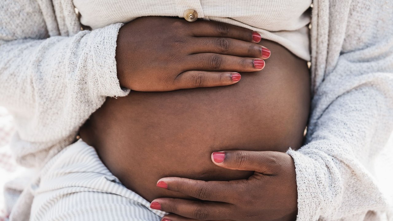 Close up of african pregnant woman holding her belly - Focus on hands