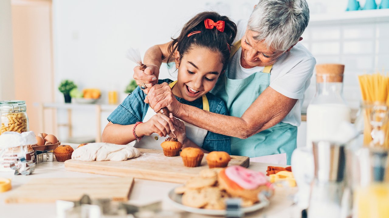 Grandmother and granddaughter preparing cupcakes together