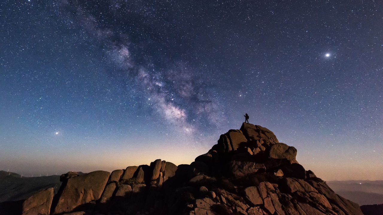 Wanderer auf einem Berg mit Milchstraße im Hintergrund