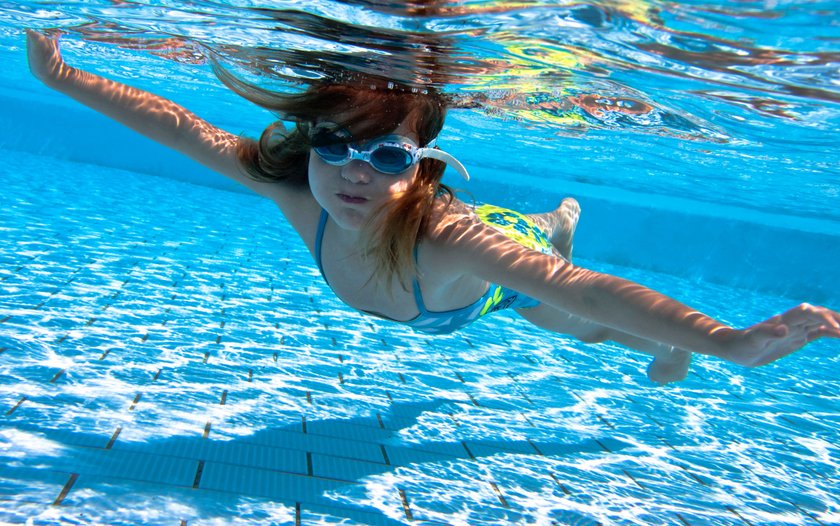 Small girl swimming under water in the pool