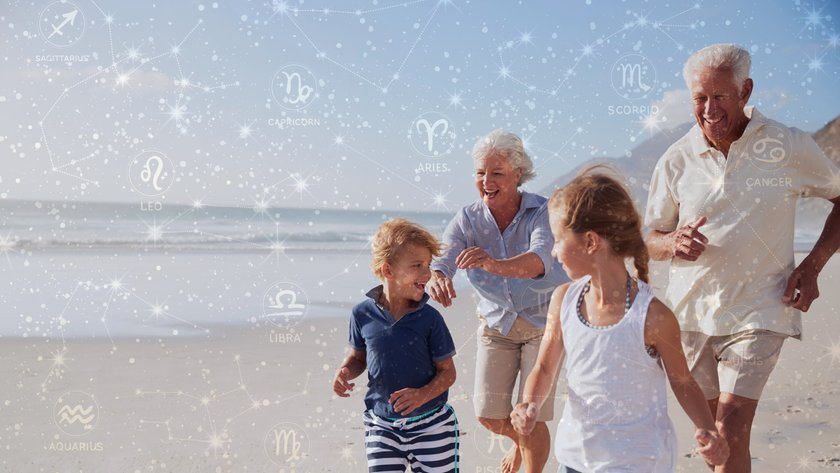 Lachende Großeltern mit Enkelkindern am Strand