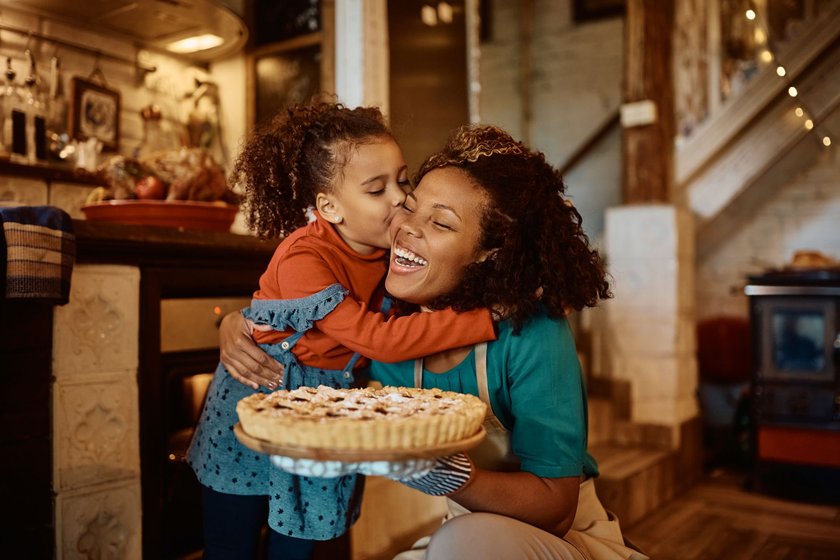 Mutter mit Tochter im Arm und Kuchen in der Hand