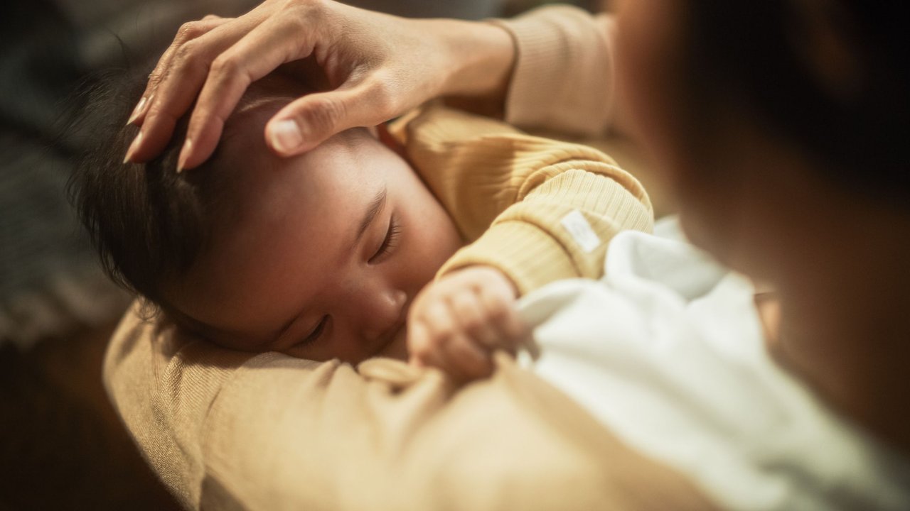 Baby heiser: Mama kuschelt schlafendes Baby