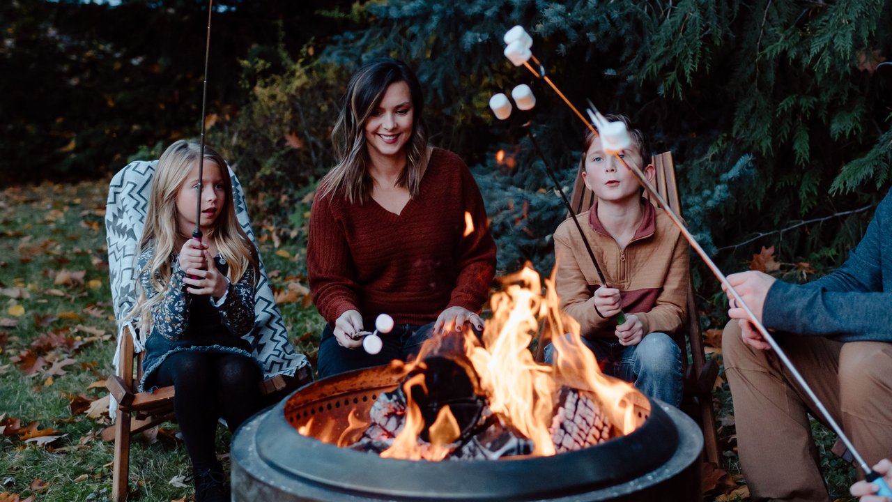 Familie sitzt im Garten zusammen um eine Feuerschale