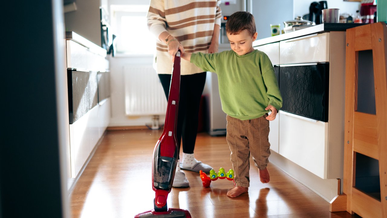 Mama saugt mit ihrem Sohn den Fußboden mit einem Wasserstaubsauger