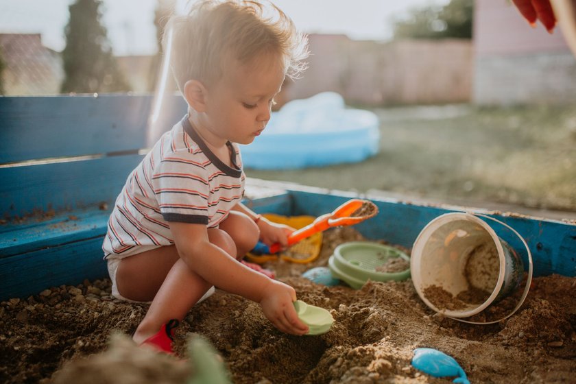Mit dem Baby sicher durch den Sommer: Kleinkind spielt im Sandkasten