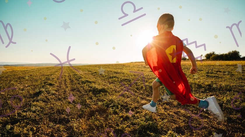 Kleiner Junge im Superheldenkostüm rennt über ein sonniges Ackerfeld