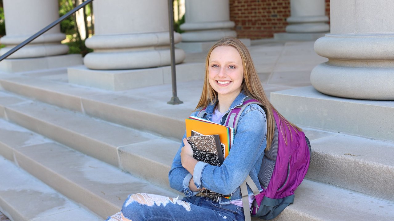 Teenaged girl poses with books in this back to school series
