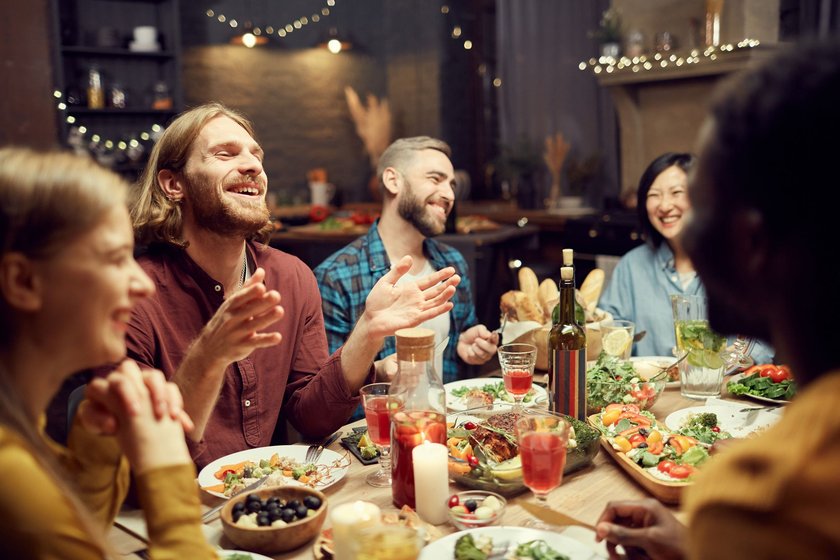 Dialekt-Challenge: Menschen lachen am Essenstisch gemeinsam über ihre Missverständnisse